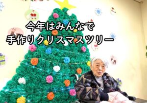 入居者がクリスマスツリーの前で手作り工作を楽しむ季節行事の風景
